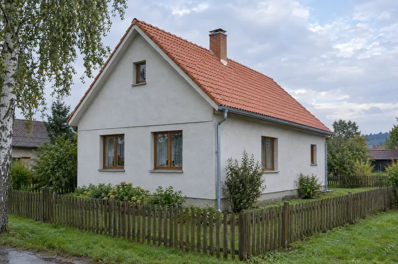 Tentýž dům po opravě: nová pálená taška v barvě terakoty, oplechování komína, nový šedý žlab a svody.
